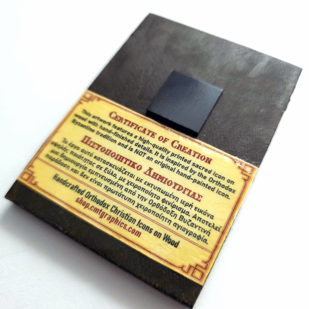 Close-up of a handmade Orthodox wooden mounted icon displayed on a natural wood surface, featuring a built-in magnet for attachment to metal surfaces and accompanied by a certificate of authenticity.