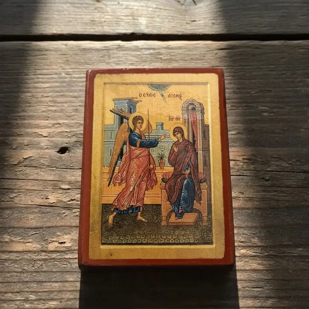 Annunciation of Theotokos Byzantine wooden-mounted icon shown at an angle on a rustic wooden surface