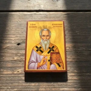 Angled close-up of a handmade wooden mounted icon featuring Saint Alexander Archbishop of Constantinople, showing the thick wood grain and glossy finish under natural sunlight.